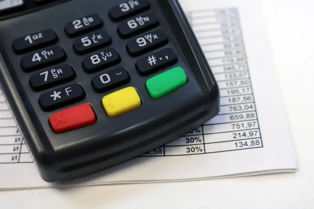 POS terminal položen preko tiskane tablice s financijskim podacima i rekapitulacijom prometa