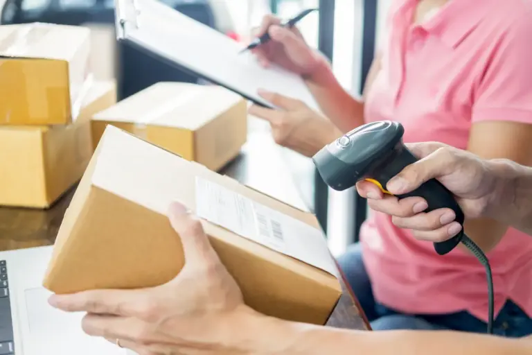 Krupni plan ruku koje koriste laserski skener barkodova za provjeru i evidenciju robe i paketa u skladištu
